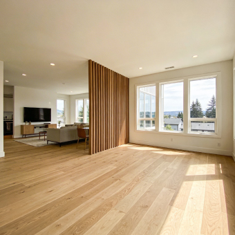 Professional painter applying white paint to interior wall with roller.